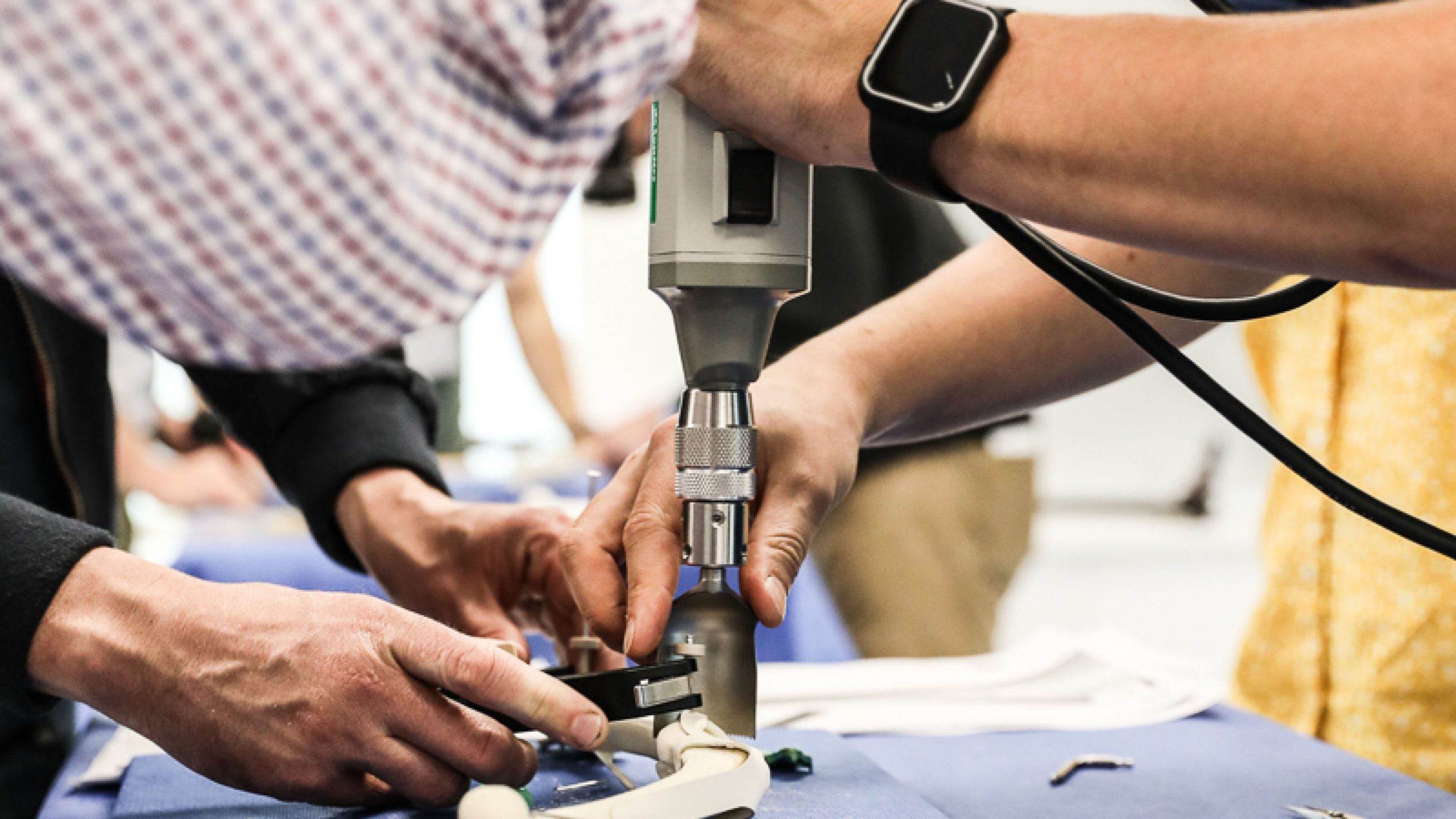 een hand-shot van twee mensen die in een dierlijk bot boren tijdens een TPLO dry lab-cursus